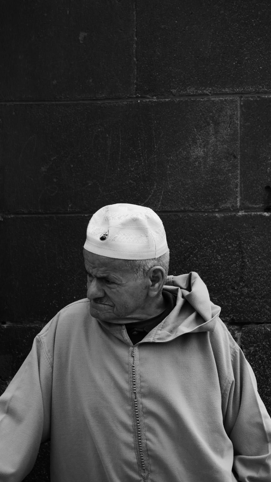 Portrait d'un homme en calotte blanche devant un mur de parpaings