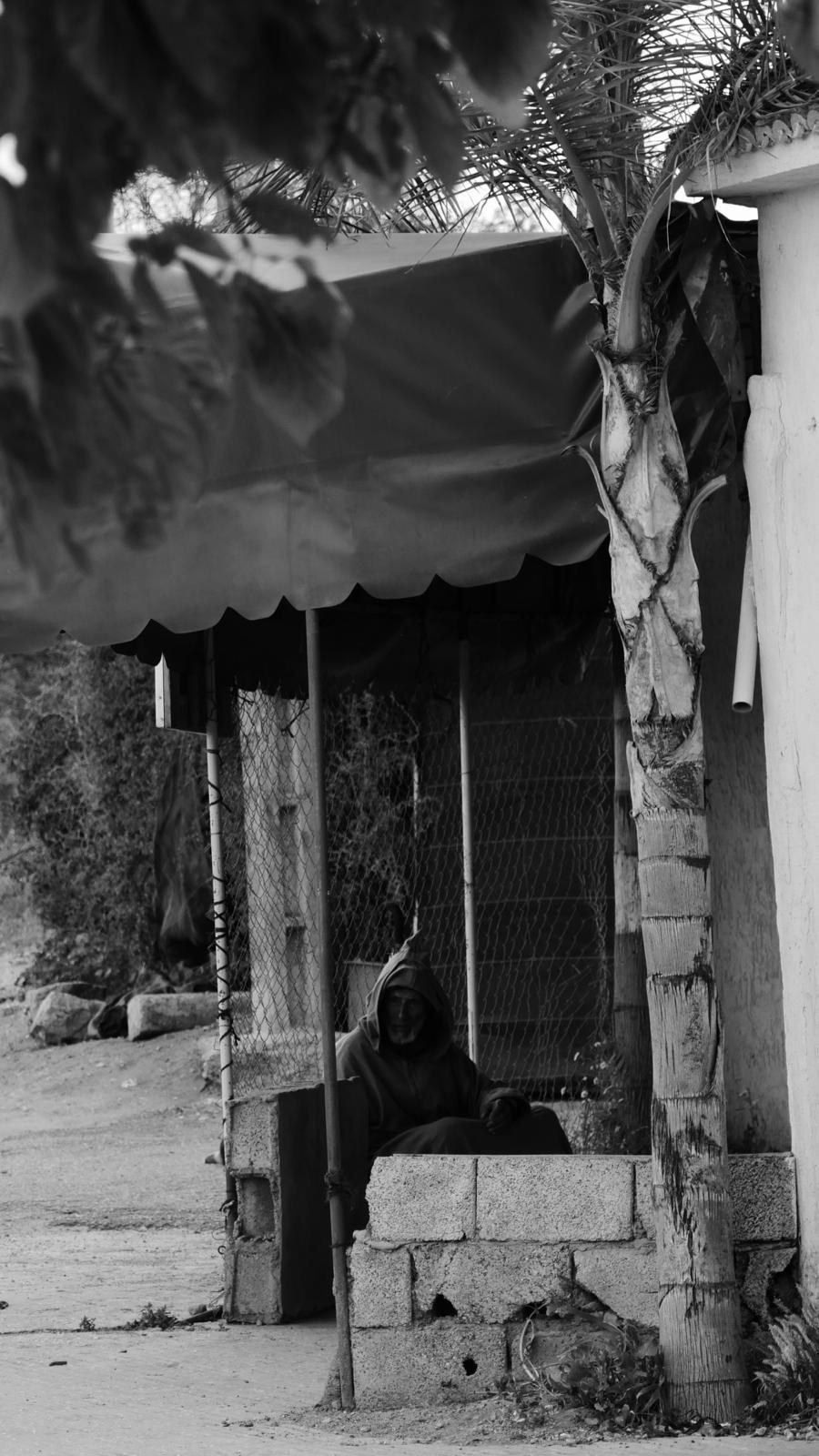 Rue en pente sous un auvent, une silhouette assise dans l'ombre
